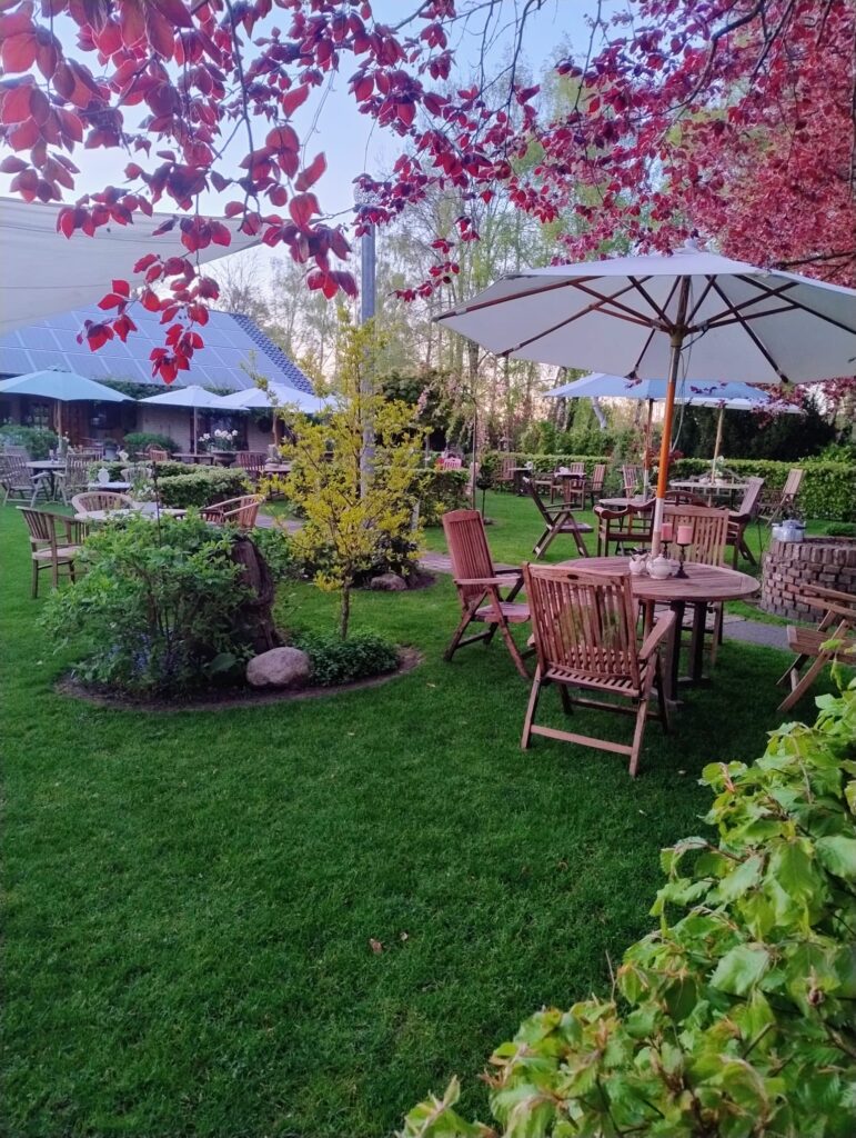 Ein gemütlicher Garten mit Holzmöbeln, Sonnenschirmen und bunten Pflanzen im Ihlow Norddeutschland 